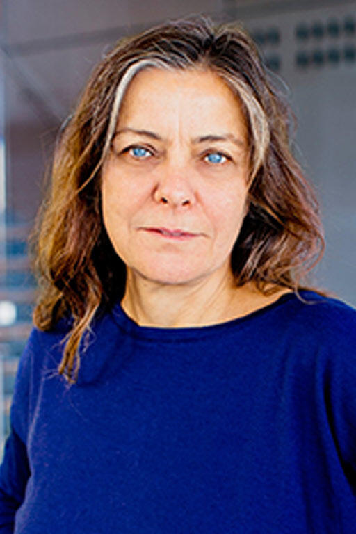Woman in a blue shirt with staircase in the background.