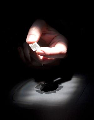 Professor Paul Alivisatos holds an experimental solar cell under a xenon light source Alivisatos holding solar cell