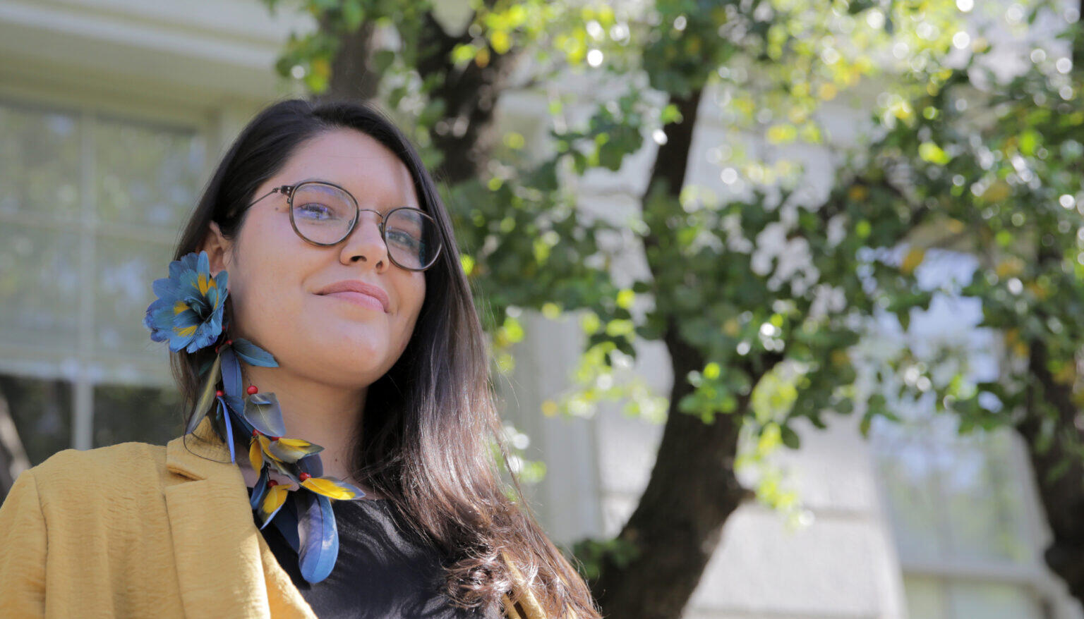 Woman in glasses wearing feather earring.