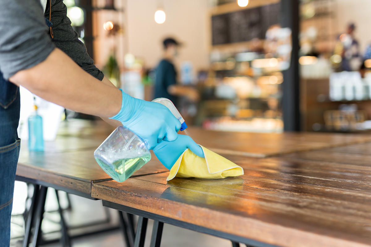 Person cleans table in a coffee shop