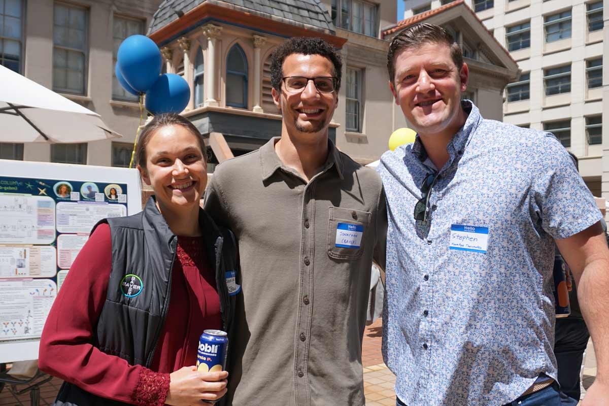 Three people smiling in front of the Cupola on the chemistry plaza.