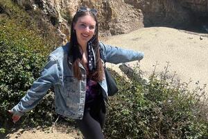 Woman in a jean jacket with arms outstretched.